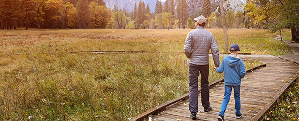 man walking down wooden path with son